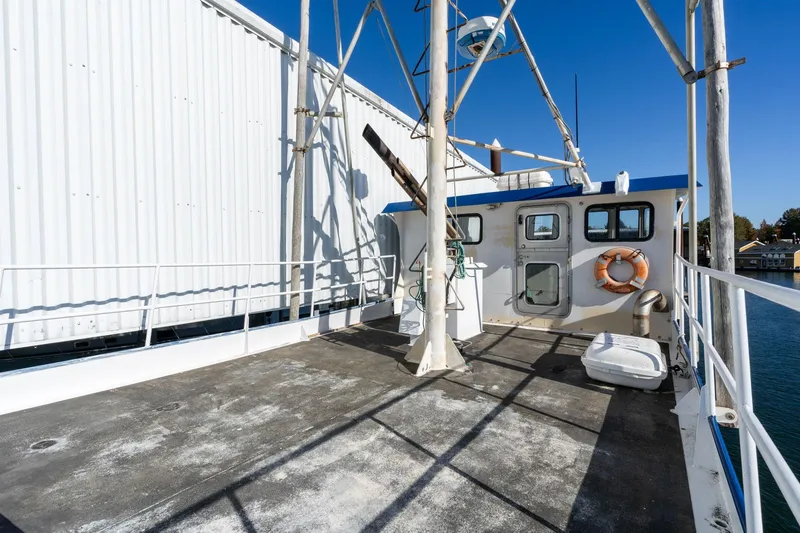 Slide: The Image of 1980 Commercial Troller boat deck with lifebuoy, docked beside a large building. - 37