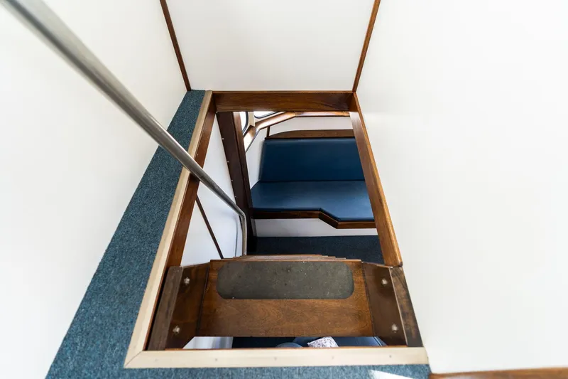 Slide: The Image of Interior view of a 1980 Commercial Troller boat, featuring a wooden staircase and blue seating. - 42