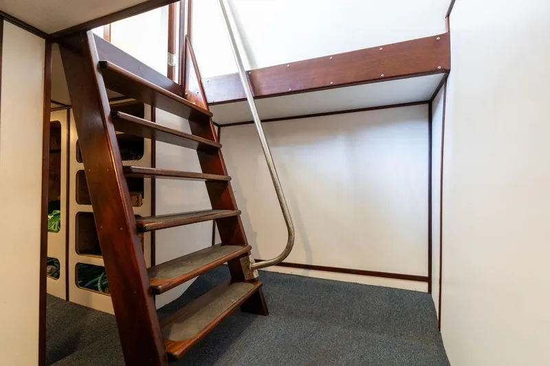 Slide: The Image of Wooden staircase inside 1980 Commercial Troller boat, featuring carpeted flooring and metal railing. - 46