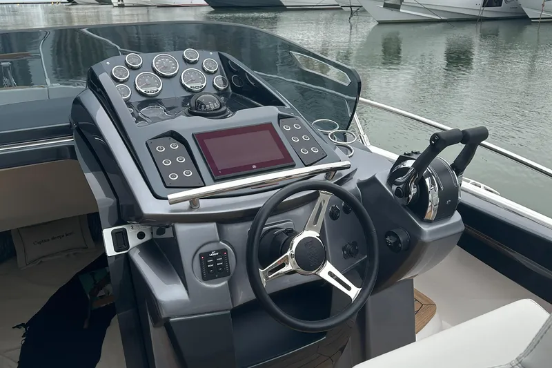 Slide: The Image of 2024 Sessa Marine Key Largo 27 Outboard Line dashboard with modern controls and steering wheel. - 11