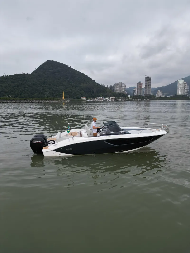 Slide: The Image of 2024 Sessa Marine Key Largo 27 boat on calm water, cityscape background. - 2