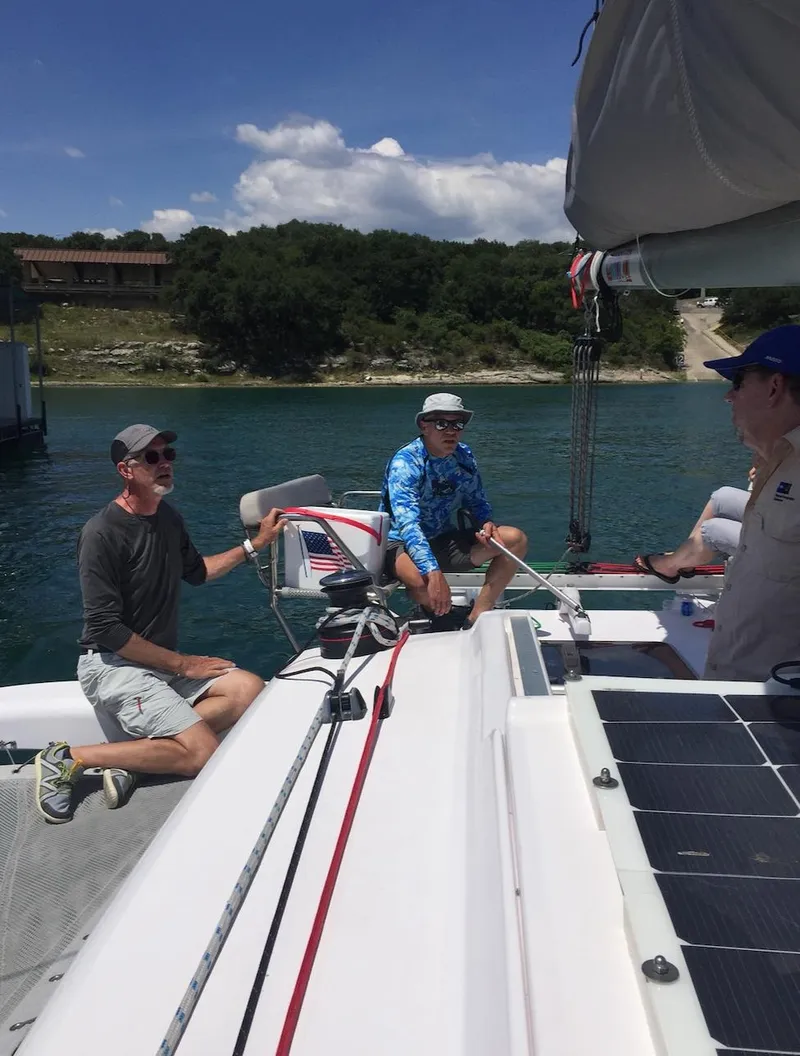 Slide: The Image of People sailing on a 2025 Corsair 970 Sport trimaran in a scenic lake setting. - 12