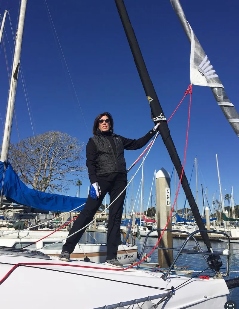 Slide: The Image of Person standing on Corsair 970 Sport sailboat, 2025 model, in a marina under clear blue sky. - 5