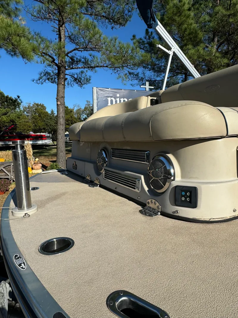 Slide: The Image of 2011 Harris 250GMSE boat with beige seating, outdoor setting, and trees in the background. - 10