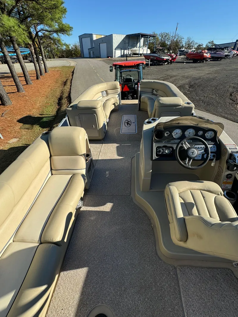 Slide: The Image of 2011 Harris 250GMSE pontoon boat with beige seating and steering console, parked outdoors. - 4
