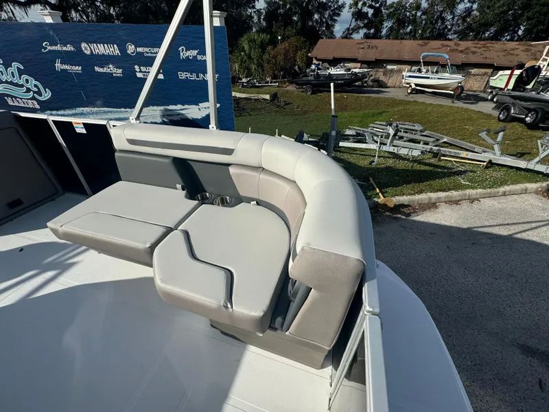 Slide: The Image of 2024 Hurricane FunDeck 2260 RE boat with comfortable seating in a marina setting. - 7