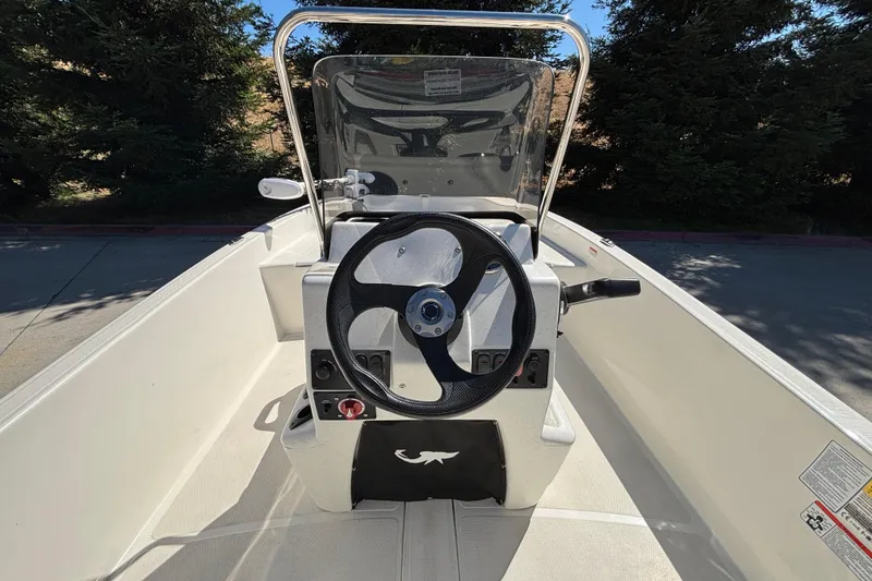 Slide: The Image of 2025 Mako Pro Skiff 17 CC boat console with steering wheel and windshield. - 18