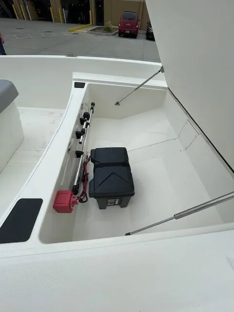 Slide: The Image of 2025 Mako Pro Skiff 17 CC boat storage compartment with battery and rods. - 6