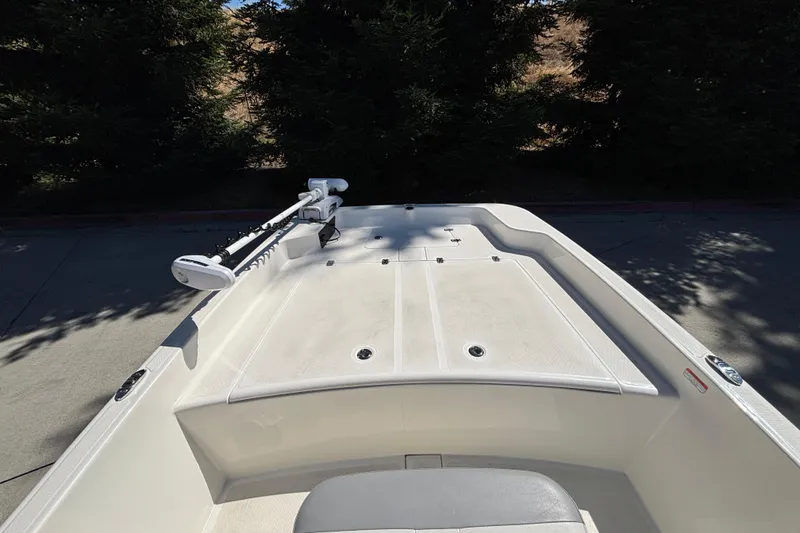 Slide: The Image of 2025 Mako Pro Skiff 17 CC boat deck with trolling motor, surrounded by trees. - 11