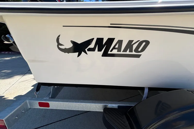 Slide: The Image of 2025 Mako Pro Skiff 17 CC boat logo on trailer, featuring shark silhouette. - 31