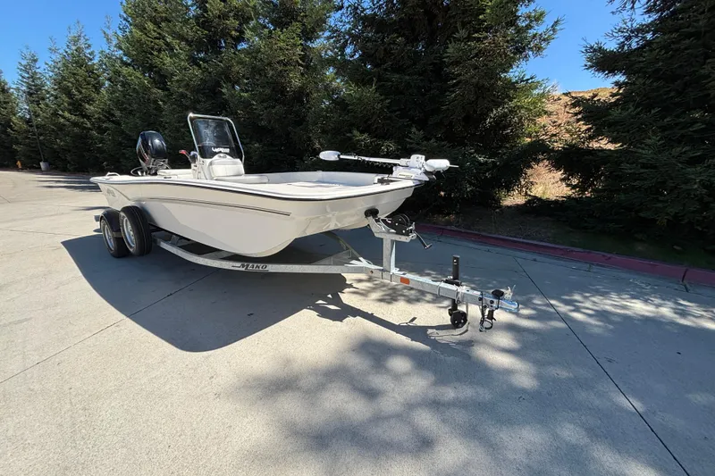 Slide: The Image of 2025 Mako Pro Skiff 17 CC boat on trailer, parked outdoors near trees. - 5