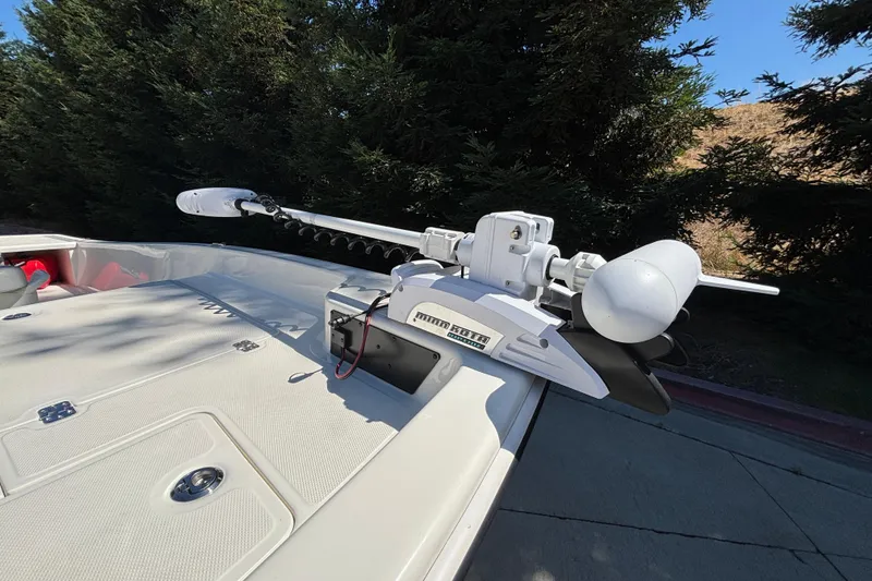 Slide: The Image of 2025 Mako Pro Skiff 17 CC boat with mounted trolling motor in a wooded area. - 15