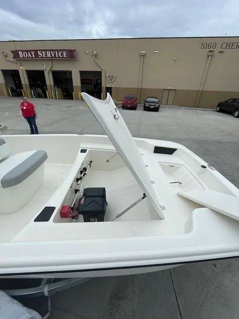 Slide: The Image of 2025 Mako Pro Skiff 17 CC boat with open storage compartment at a service center. - 9