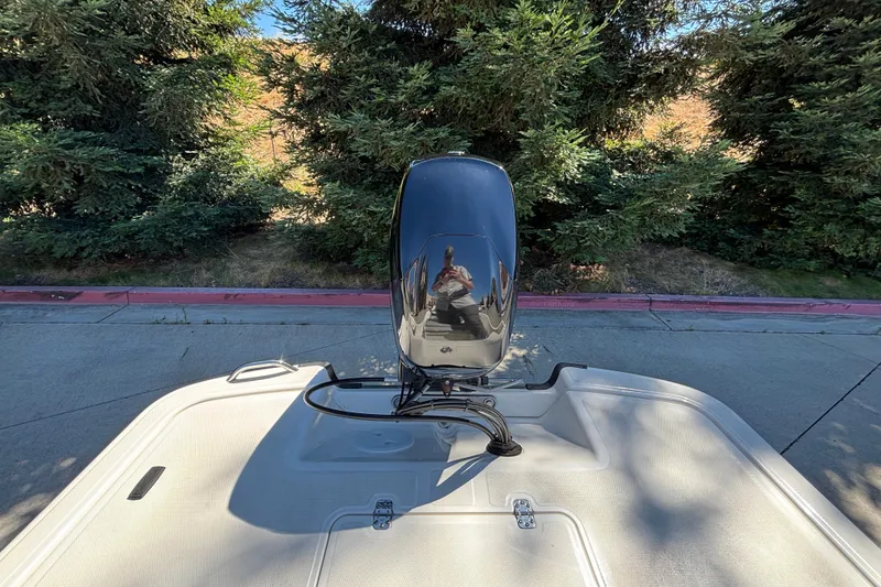 Slide: The Image of 2025 Mako Pro Skiff 17 CC boat with outboard motor, parked near lush greenery. - 10