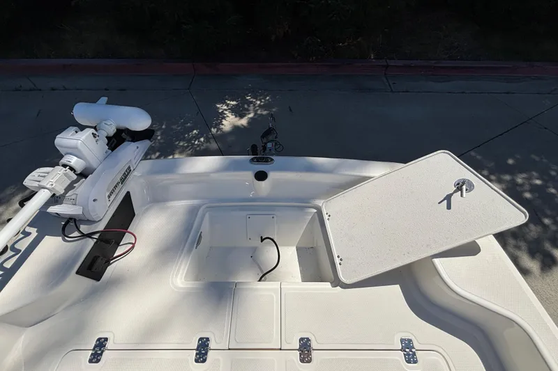 Slide: The Image of 2025 Mako Pro Skiff 17 CC boat deck with open storage compartment and trolling motor. - 14
