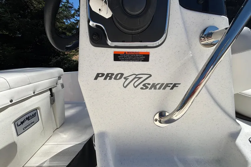 Slide: The Image of 2025 Mako Pro Skiff 17 CC boat interior with steering console and branding. - 23