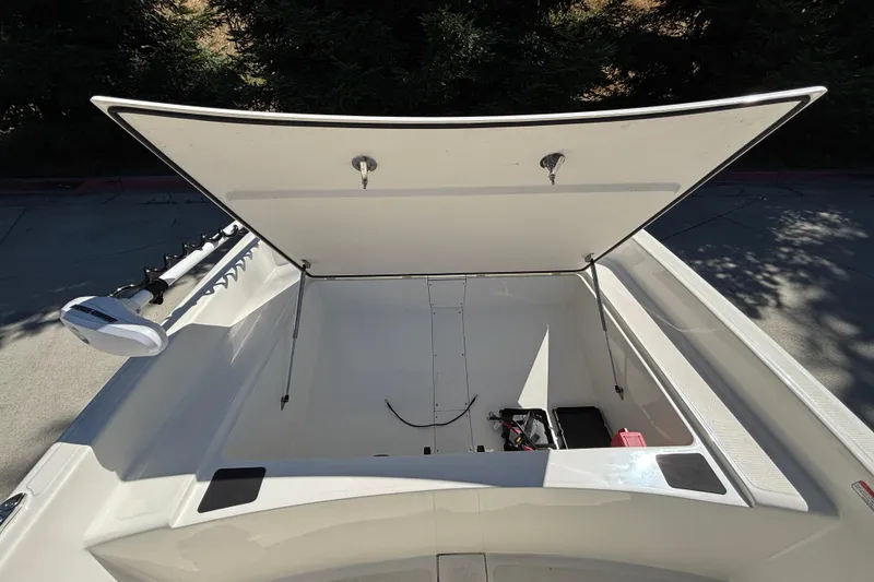 Slide: The Image of 2025 Mako Pro Skiff 17 CC boat storage compartment open, showing interior space. - 12