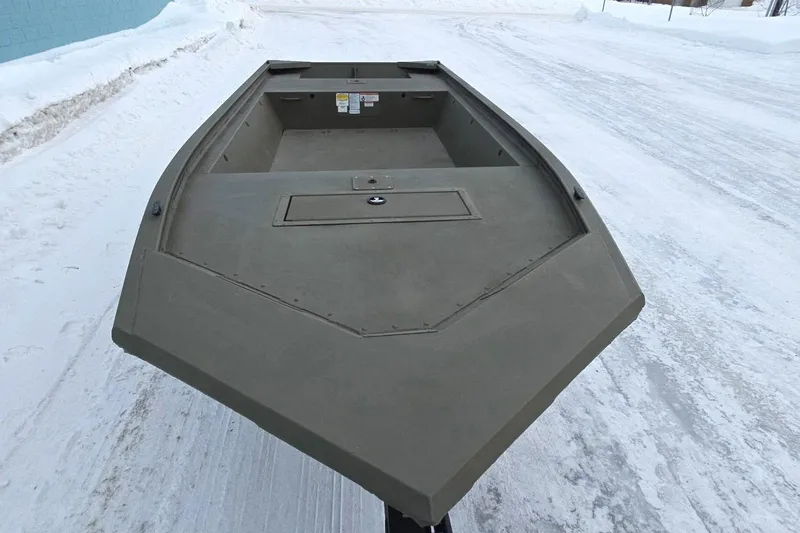 Slide: The Image of 2025 Tracker Grizzly 1648 Jon boat on snowy ground, showcasing its sturdy design. - 2