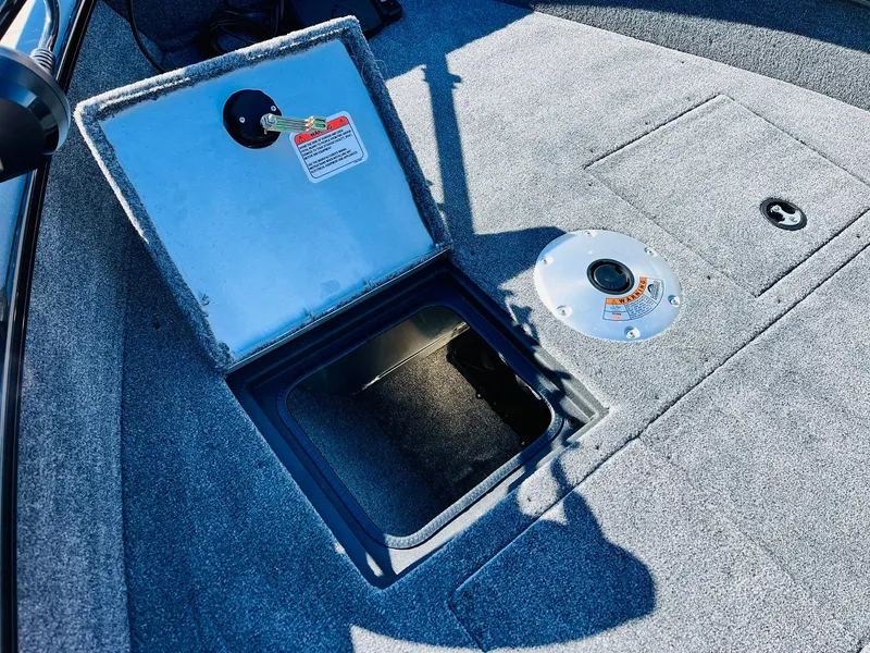 Slide: The Image of 2025 Tracker Pro Guide V-16 SC boat storage compartment with open hatch and carpeted floor. - 11