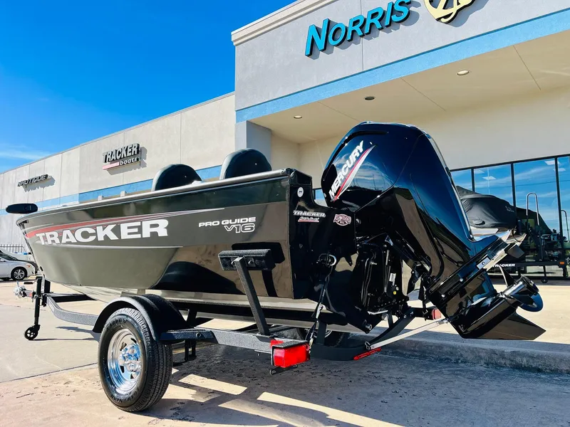 Slide: The Image of 2025 Tracker Pro Guide V-16 SC boat outside dealership, featuring sleek black design. - 6