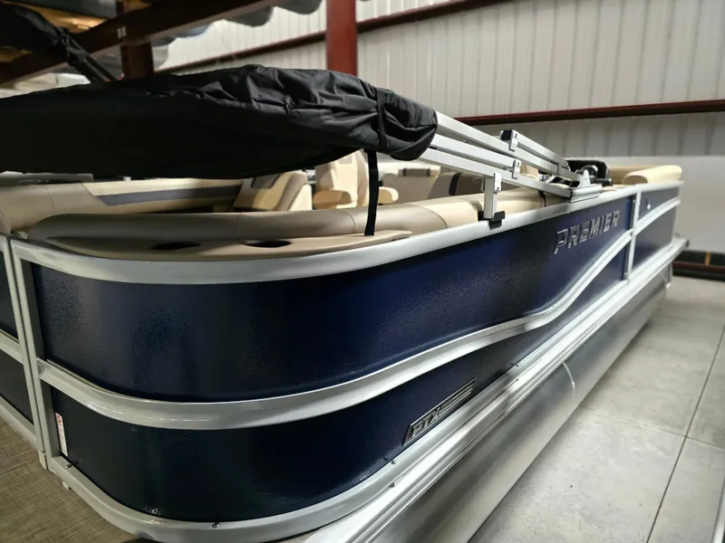 Slide: The Image of 2025 Premier 220 Sunscape RF pontoon boat in storage, featuring sleek blue exterior design. - 2