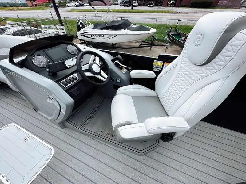Slide: The Image of 2025 Godfrey Monaco 23' Tritoon helm with luxurious white captain's chair and modern dashboard. - 10