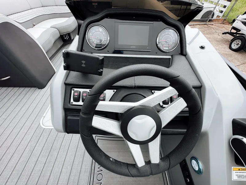 Slide: The Image of 2025 Godfrey Monaco 23' Tritoon helm with modern steering wheel and dashboard controls. - 11
