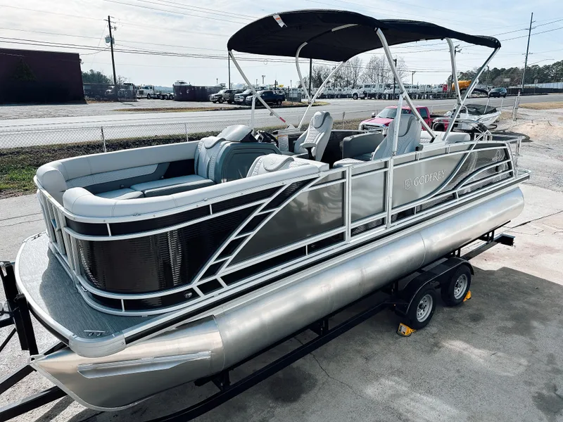 Slide: The Image of 2025 Godfrey Monaco 23' Dual Flip Lounge Tritoon on trailer, sleek design, outdoor setting. - 11