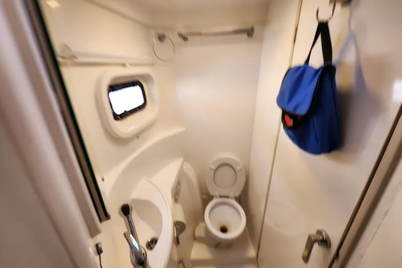 Slide: The Image of Compact bathroom in a 2015 Leopard 44 yacht with toilet, sink, and porthole. - 156