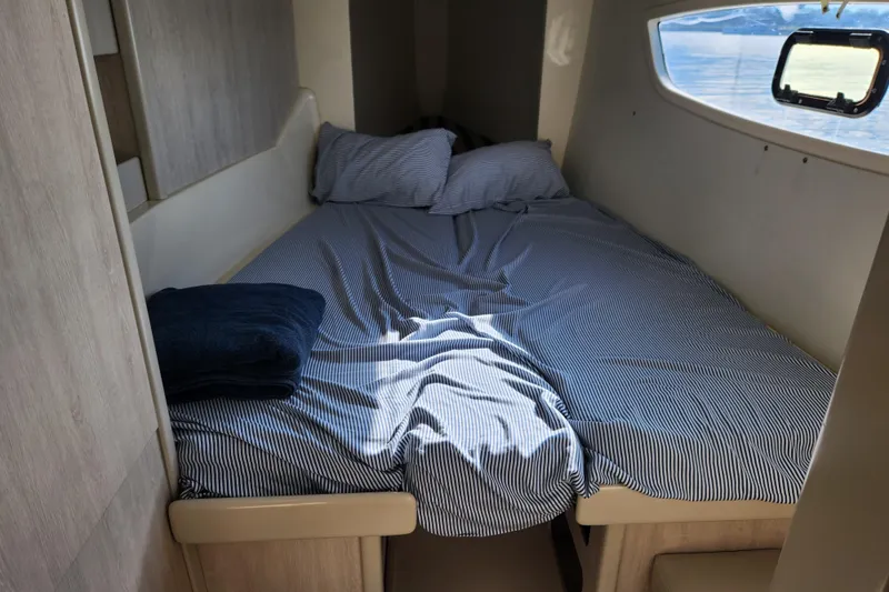Slide: The Image of Cozy cabin bed in 2015 Leopard 44 yacht with striped bedding and window view. - 164