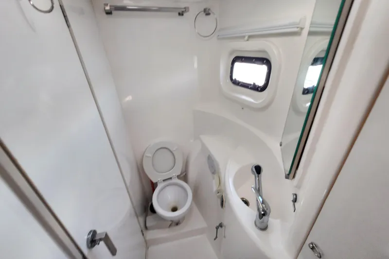 Slide: The Image of Compact bathroom in a 2015 Leopard 44 yacht with toilet, sink, and porthole window. - 171