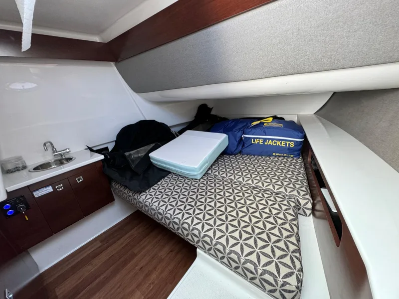 Slide: The Image of 2022 Chaparral 300 OSX cabin interior with bed, sink, and life jackets. - 29