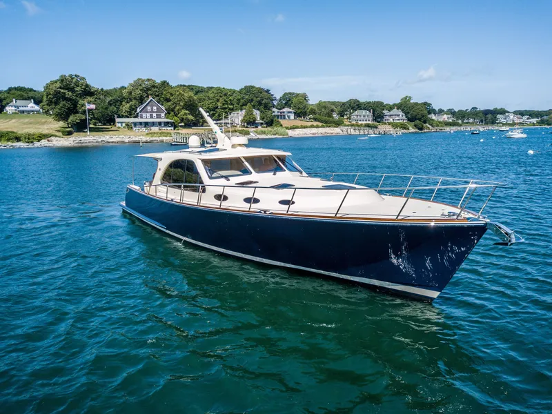 The Image of 2026 Palm Beach Motor Yachts PB52 cruising on serene blue waters near a coastal landscape. - 0
