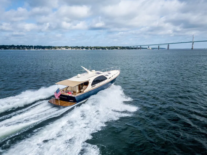 Slide: The Image of 2026 Palm Beach Motor Yachts PB52 cruising on open water near a bridge under cloudy skies. - 21