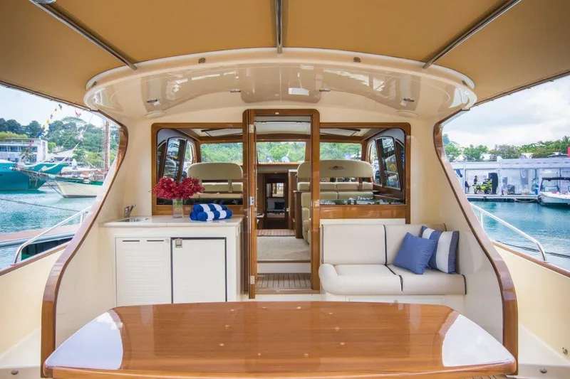 Slide: The Image of 2026 Palm Beach Motor Yachts PB52 interior with elegant seating and wooden table, docked at marina. - 7