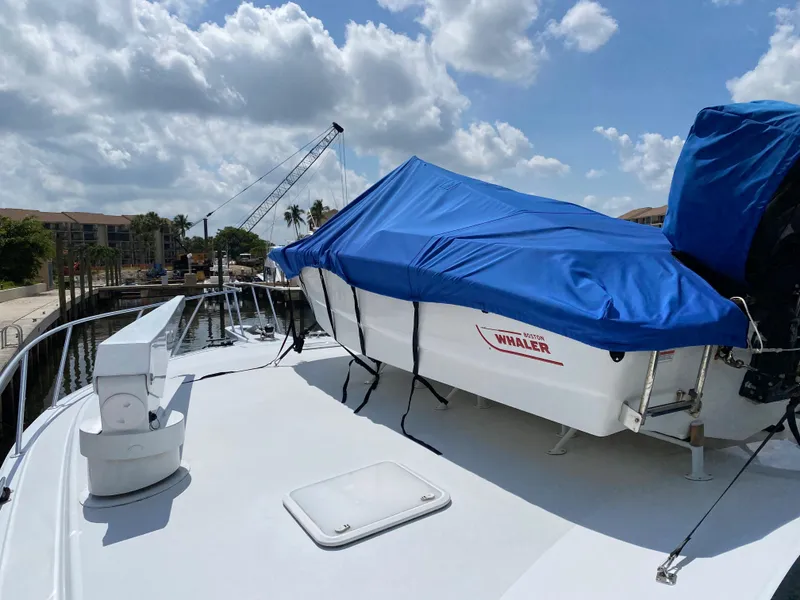 Slide: The Image of 2003 Viking 65 Convertible Enclosed Bridge yacht with covered boat on deck, docked under cloudy sky. - 42