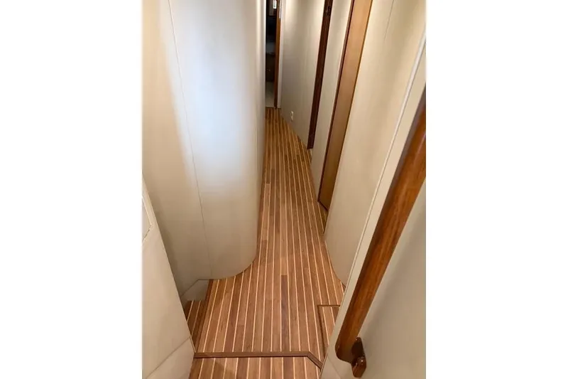 Slide: The Image of Narrow hallway with wooden flooring inside a 2003 Viking 65 Convertible Enclosed Bridge yacht. - 74