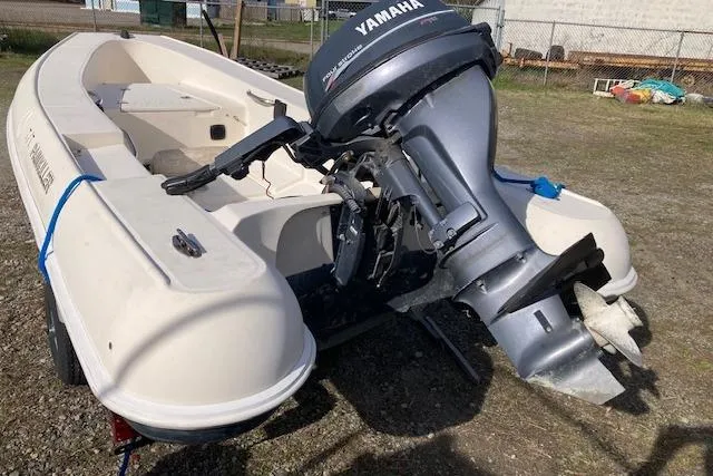 The Image of Small white Jouet 13 boat with Yamaha outboard motor, 1998 model, parked on grass. - 0