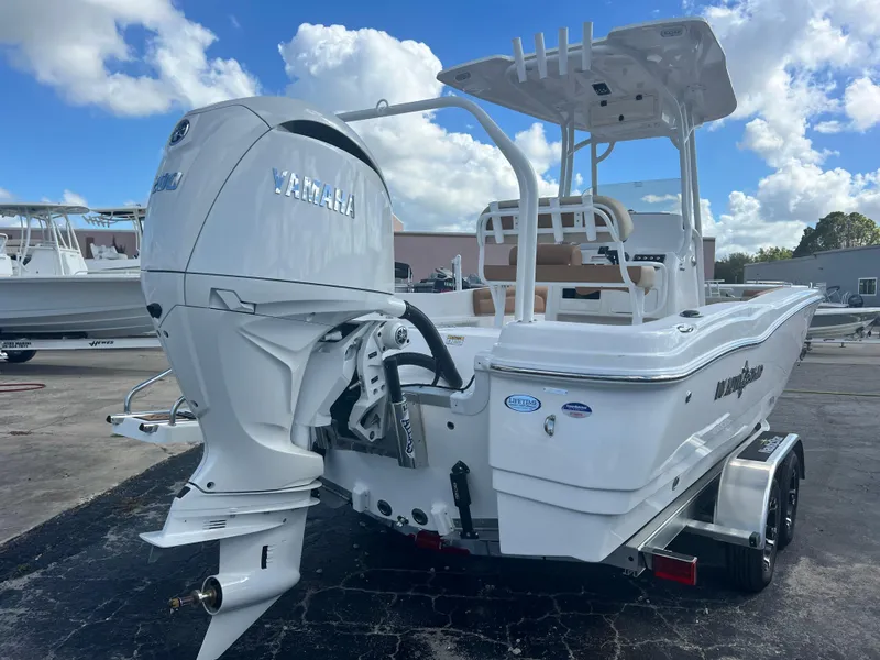 Slide: The Image of 2025 NauticStar 231 Hybrid boat with Yamaha engine, parked on a trailer under a blue sky. - 10