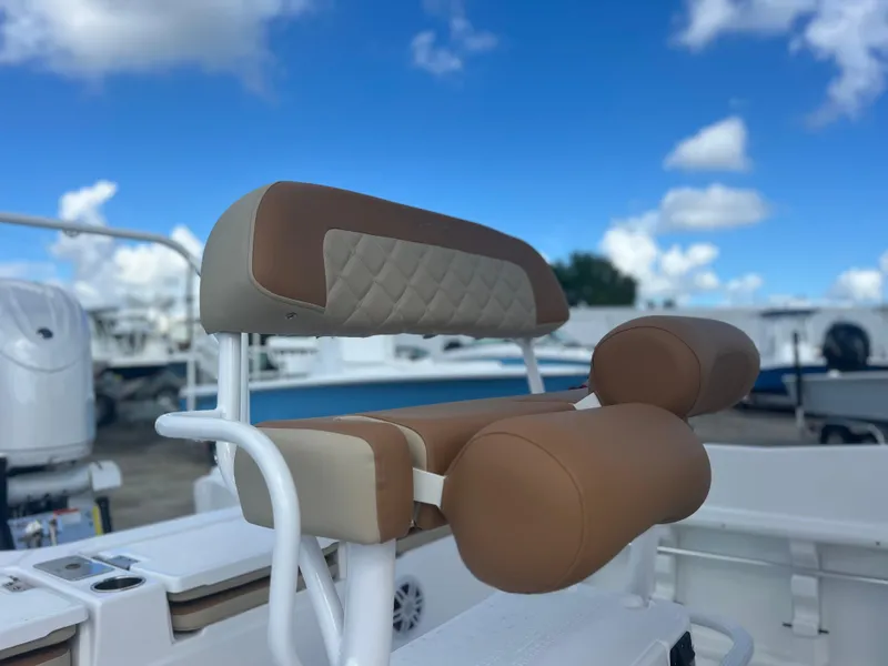 Slide: The Image of 2025 NauticStar 231 Hybrid boat seat with brown upholstery, outdoor marina setting. - 4