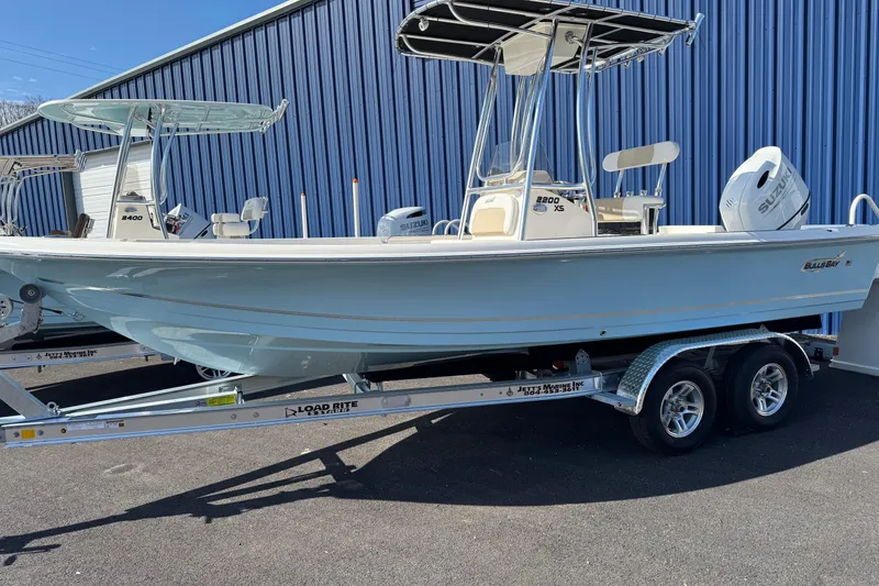 Slide: The Image of 2026 Bulls Bay 2200 XS boat on trailer, parked near blue building. - 16