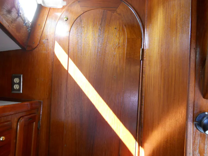 Slide: The Image of Wooden interior of a 1979 Morgan 382 sailboat, featuring a door and sunlight. - 5