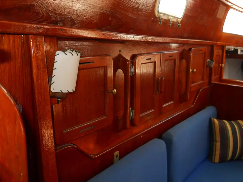 Slide: The Image of Interior of 1979 Morgan 382 sailboat with wooden cabinets and blue seating. - 8