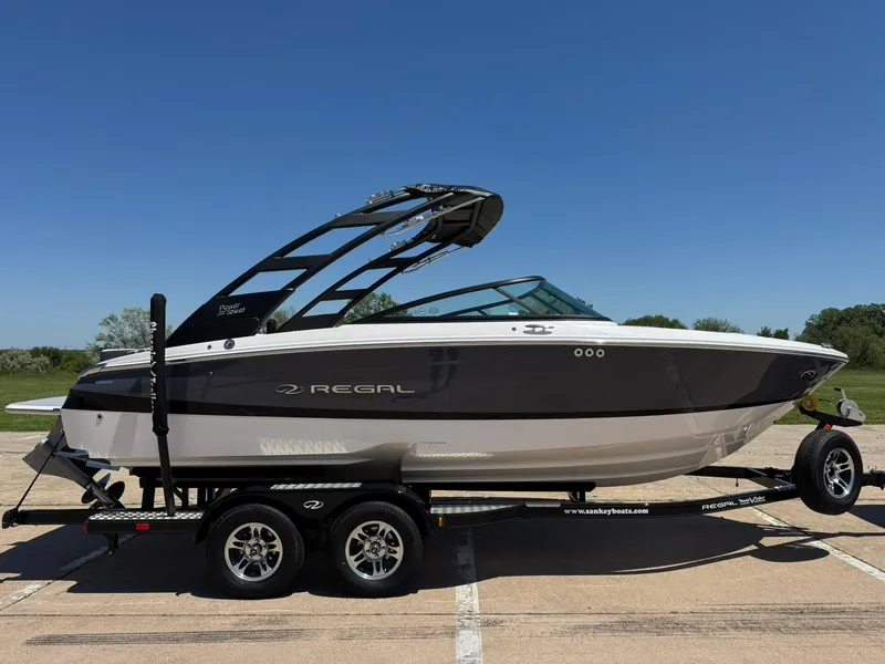 Slide: The Image of 2025 Regal LS2 Surf boat on trailer under clear blue sky. - 11