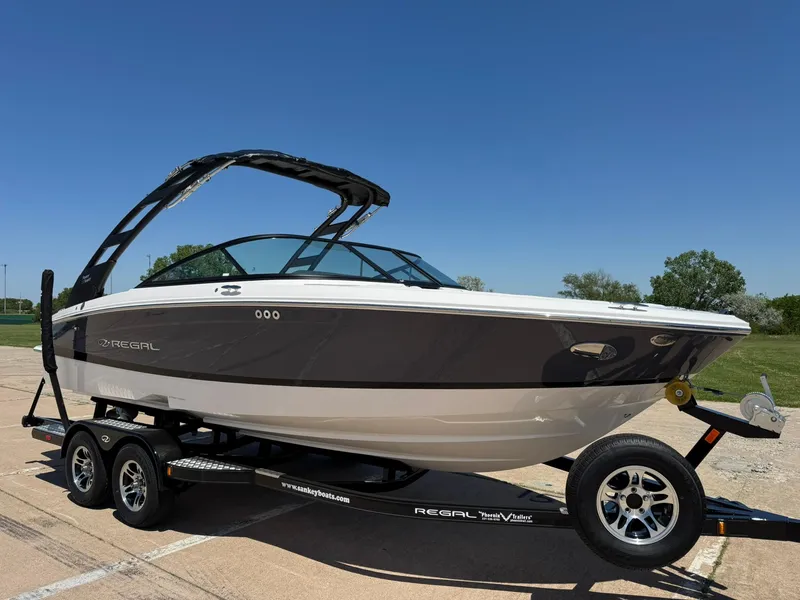 Slide: The Image of 2025 Regal LS2 Surf boat on trailer under clear blue sky. - 12