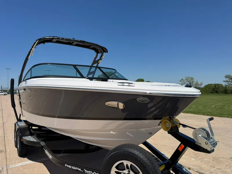 Slide: The Image of 2025 Regal LS2 Surf boat on trailer under clear blue sky. - 13