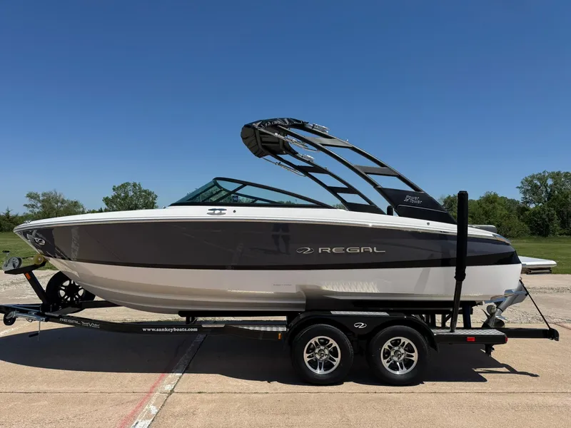 Slide: The Image of 2025 Regal LS2 Surf boat on trailer, sleek design, parked outdoors. - 2