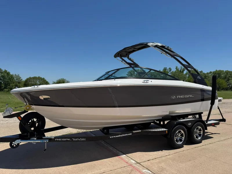 Slide: The Image of 2025 Regal LS2 Surf boat on trailer, parked outdoors on a sunny day. - 3