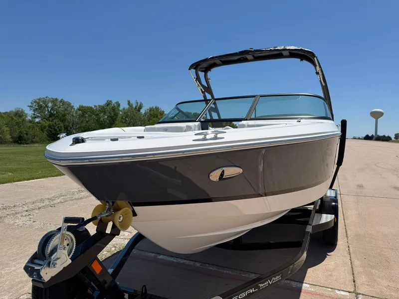 Slide: The Image of 2025 Regal LS2 Surf boat on trailer, parked outdoors under clear blue sky. - 5