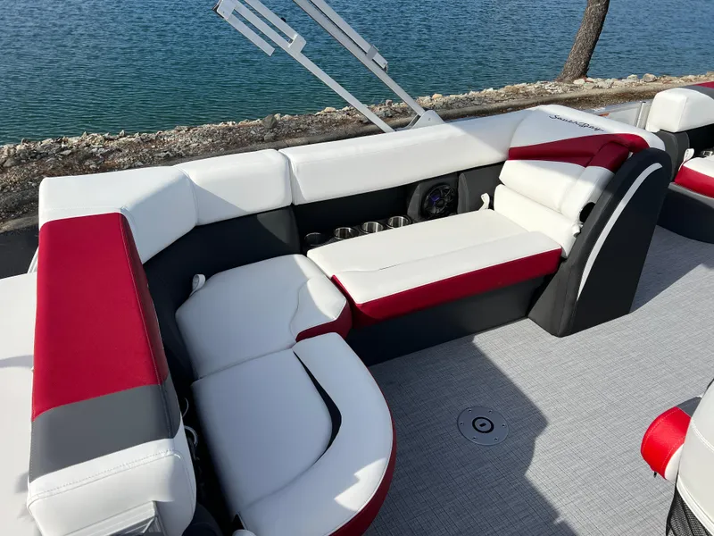 Slide: The Image of 2025 South Bay S 220 CR2 pontoon boat interior with red and white seating by the water. - 17